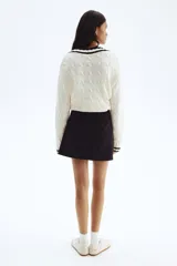 Minifalda negra con cintura estándar, cierre lateral oculto y pliegues de tabla delanteros.