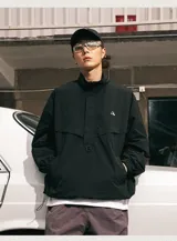 Chaqueta tipo anorak impermeable de color negro, con cuello alto y cierre parcial frontal. Presenta un pequeño logo en el pecho y ajuste regulable en la cintura para un calce más holgado o ceñido.