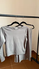 Remera gris de manga larga con cuello tipo bote, confeccionada en jersey térmico.