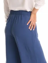 Pantalón palazzo azul de crepe, con tiro alto, pretina lisa en la parte delantera y elastizada en la parte posterior. Presenta doble pinza en la delantera y bolsillos funcionales.