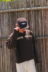 Buzo de tejido marrón con cuello polo y cierre parcial. Presenta un patrón texturado de espiga y el estampado frontal en blanco con el texto "glassywave".