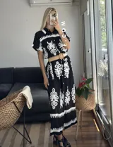 Vestido camisero largo negro con estampado de flores blancas y cinto incluido.