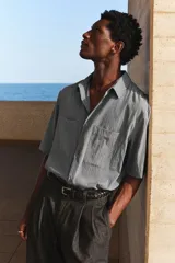 Camisa de manga corta color gris con dos bolsillos frontales con solapa y cierre de botones.