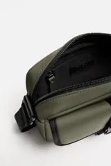 Bandolera negra de acabado engomado, con compartimento principal con cierre de cremallera y bolsillo interior con cremallera. Bolsillo frontal con cierre de hebilla de liberación rápida. Asa de hombro ajustable y extraíble.