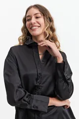 Camisa negra de manga larga confeccionada en tela satinada.