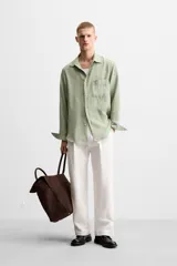 Camisa verde claro de corte relaxed fit confeccionada en tejido con mezcla de modal. Tiene cuello italiano, manga larga con puños abotonados, bolsillo de parche en el pecho y cierre frontal abotonado.