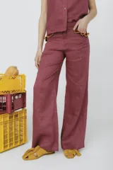 Pantalón de vestir color borgoña, de corte palazzo y tiro alto, con bolsillos laterales y detalle de volados en la cintura.