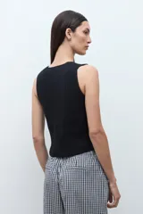 Chaleco de punto color beige melange, con escote en V y cierre frontal de dos botones oscuros. Es sin mangas y de corte ajustado.