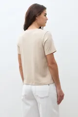 Remera de manga corta color beige melange, con cuello redondo y calce al cuerpo.