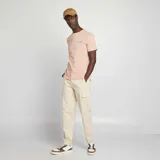 Camiseta rosa pálido de manga corta con cuello redondo y estampado pequeño en el pecho con la palabra "Oranges".
