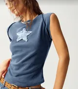 Remera color beige de tejido acanalado, corte ajustado, cuello redondo y mangas cortas. Tiene un parche de estrella color borgoña en el pecho.