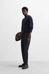 Pantalón slim fit negro confeccionado en tejido con elasticidad en ambas direcciones. Cuenta con bolsillos frontales y traseros de vivo con botón. Cierre frontal con cremallera y botón.