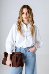 Camisa blanca de manga larga con detalles de encaje en el frente y cuello mao.