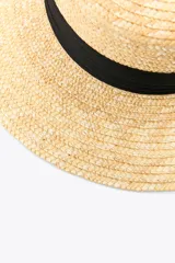 Sombrero de paja natural con ala ancha y cinta negra contrastante alrededor de la base de la copa.