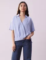 Blusa celeste de lino marca Cupio, con cuello con solapa, escote en V y delantera cruzada.