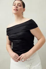 Top negro con escote off-shoulder, confeccionado en tejido de punto con efecto satinado y corte ajustado.