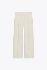Pantalón de tiro alto color crudo con finas rayas verticales negras, pinzas delanteras, bolsillos frontales y falsos bolsillos de vivo en la espalda.