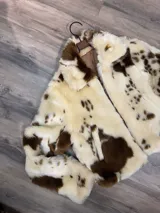 Campera corta de piel sintética con estampado vacuno en tonos crema y marrón chocolate, corte recto y forro interior.