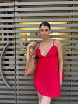 Vestido corto color fucsia con breteles finos, escote en V y falda escalonada.