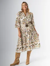 Vestido midi de algodón italiano, color blanco con estampado boho chic en tonos naranja, marrón y verde. Tiene corte oversized, mangas 3/4 con volados y cinturón de soga trenzada con hebilla circular.