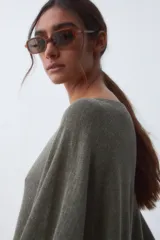 Poncho tejido de color verde militar, con cuello bote y corte holgado.