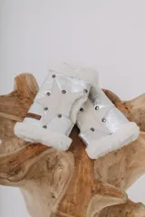 Par de guantes sin dedos plateados con aplique de estrella blanca, tachas metálicas y borde de lana blanca.