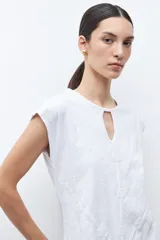 Remera verde petróleo con cuello redondo y abertura en forma de lágrima en el escote. Presenta un estampado geométrico en relieve y mangas cortas.