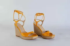 Sandalias de cuero color naranja con plataforma de yute y tiras para atar en el tobillo.