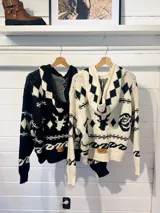 Camperón tejido oversize con capucha, bolsillos y estampa de ciervo.