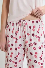 Pijama de dos piezas: remera rosa claro de manga corta con un pequeño bordado de labios en el pecho, y pantalón largo con estampado integral de labios en tonos rosados y bordó.