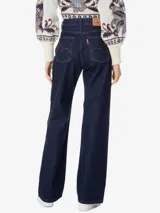 Pantalón de jean azul oscuro de corte ancho, con cintura alta, pretina con trabillas, cinco bolsillos y cierre frontal con botón y cremallera.