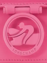 Bandolera Longchamp modelo Box-Trot XS, color fucsia, con correa fina ajustable y logo circular metálico en el frente.