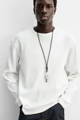 Camiseta blanca de manga larga con cuello redondo y textura cuadriculada.