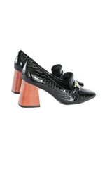 Zapato mocasín de cuero negro con estampado brillante y detalle metálico dorado en la parte delantera. Tiene taco geométrico escultural color madera.