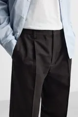 Pantalón de vestir negro de corte recto, con cintura elástica, pliegues frontales, bolsillos laterales y traseros.