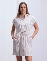 Vestido camisero corto con estampado de rayas verticales celestes y blancas. Tiene cuello camisero, mangas cortas con dobladillo, cierre frontal con botones y cinturón de lazo en la cintura.