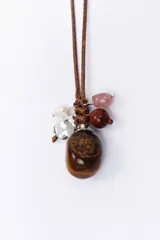 Collar con cordón marrón y dije de piedra ojo de tigre, con cuentas de cristal rosado, marrón y plateado.