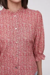 Blusa estampada con flores azules y hojas verdes, cuello mao con volados, mangas 3/4 con volados en los puños y cierre frontal con botones.