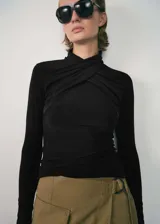 Camiseta negra de cuello alto con diseño cruzado y mangas largas.