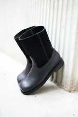 Botas de cuero vacuno color negro, con caña media y suela de caucho.