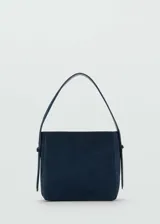 Bolso de hombro azul marino de piel serraje con forro interior y cierre de botón magnético. Tiene asa de mano y asa de hombro ajustable.
