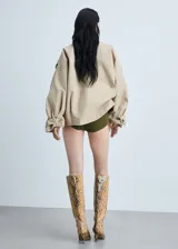 Abrigo color beige con cierre delantero con botones cruzados, cuello camisero, manga larga con trabillas, diseño corto y recto, dos bolsillos laterales y forro interior.