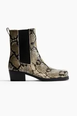 Botas Chelsea de mujer con estampado de piel de serpiente en tonos beige, negro y marrón. Presentan punta y taco cuadrados, elásticos laterales negros y una trabilla trasera para facilitar el calce.