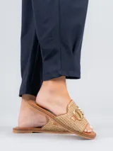 Sandalias bajas color beige con diseño tejido y detalle de hebilla dorada.