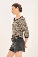 Sweater de punto ajustado al cuerpo con estampado de leopardo en tonos beige y negro. Presenta cuello redondo, mangas tres cuartos y ribetes negros en cuello, puños y ruedo. Contiene hilados de lurex.