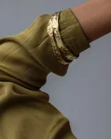 Brazalete rígido dorado con textura irregular.