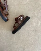 Sandalias de cuero vacuno color negro, con tiras finas y suela plana.