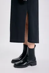 Vestido negro de corte recto y largo midi, con cuello redondo y mangas globo cortas. Presenta pespuntes contrastantes en color claro que recorren el frente y los hombros.