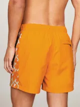 Short de baño naranja con estampado de monogramas TH en blanco a lo largo de la pierna.