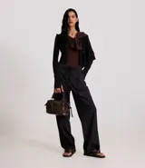 Pantalón wide leg negro confeccionado en cupro, con lazo en la cintura y bolsillos cargo en los laterales.
